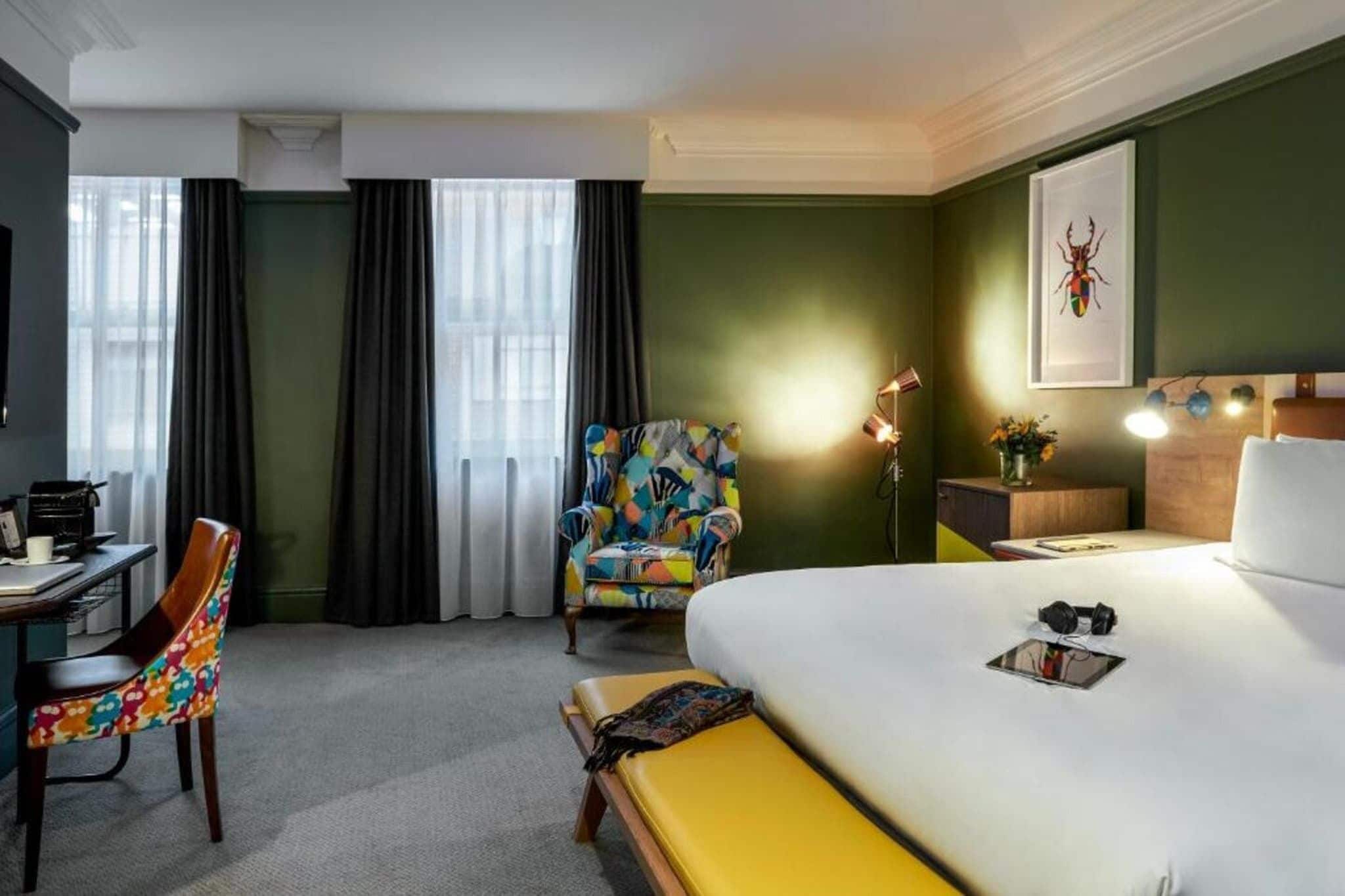 A hotel room with a bed, a desk, a chair, and a window with curtains.