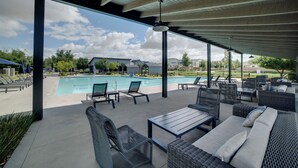 Un espace extérieur abrité comprenant une piscine, des chaises longues et des coins salon.