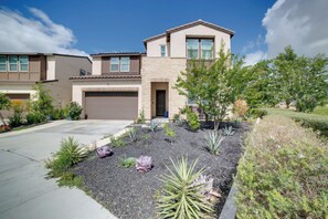 A residential house with a garage, a driveway, and landscaped garden with various plants. - Premium Ontario Home w/ Resort-Style Perks! (Ontario)