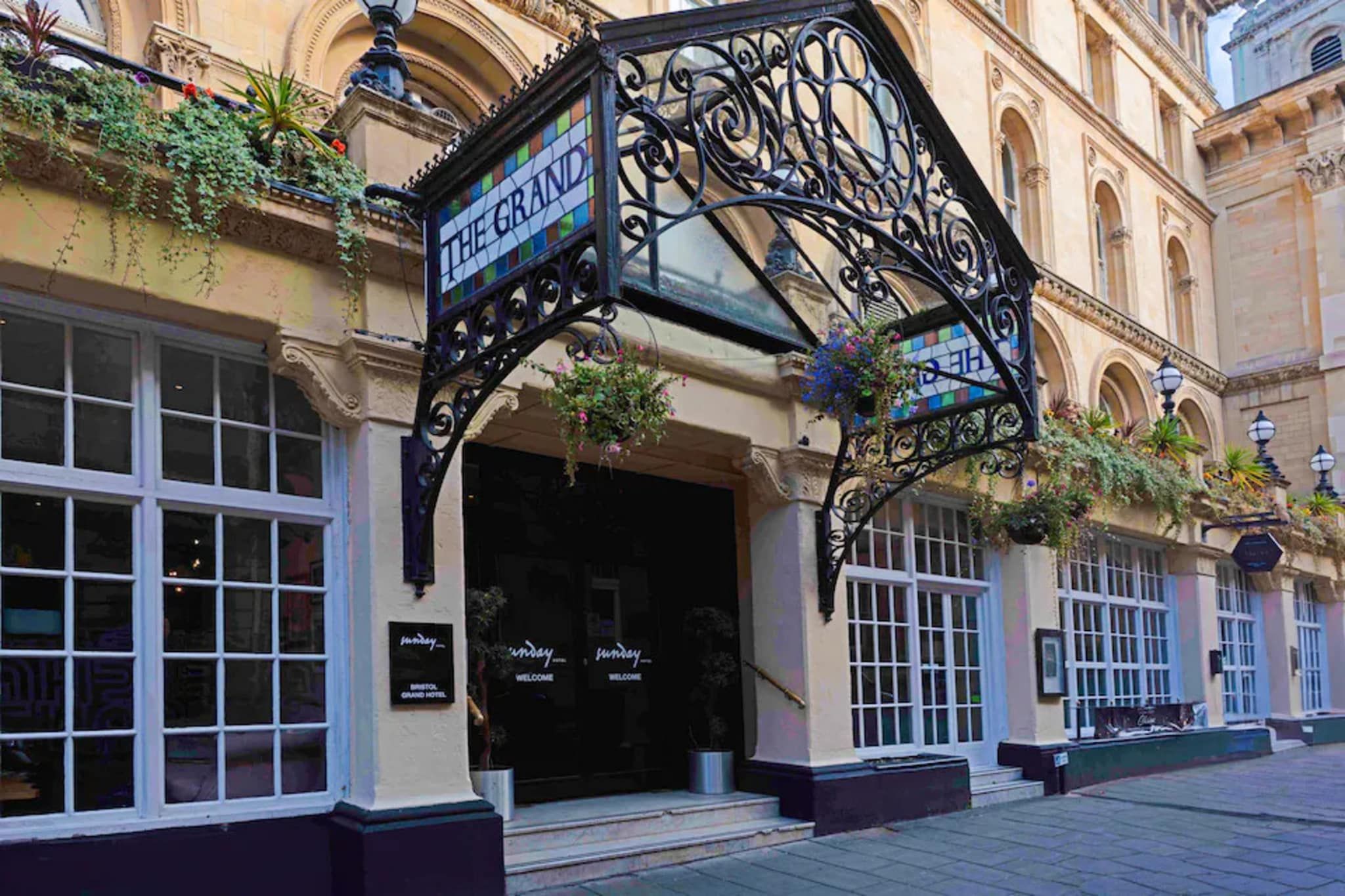 A building with a sign reading 'THE GRAND HOTEL' and a welcoming sign at the entrance.
