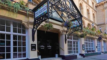 A building with a sign reading 'THE GRAND HOTEL' and a welcoming sign at the entrance.