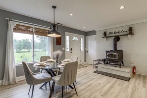 A dining area with a glass table, chairs, and a hanging light fixture.