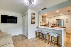 A modern kitchen with white cabinets, a stainless steel refrigerator, and a bar area with stools. - Patio & Grill: Waterfront Lake Helen Escape! (Lake Helen)