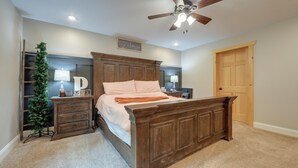 A bedroom with a wooden bed, a ceiling fan, a Christmas tree, and a door. - Pet Friendly Family Getaway on 15 Acres! (Gouverneur)