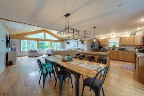 A spacious kitchen with wooden cabinets, a central island, and a dining area with chairs and a table.