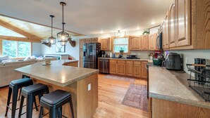 A modern kitchen with wooden cabinets, a central island with stools, a refrigerator, and a coffee maker. - Pet Friendly Family Getaway on 15 Acres! (Gouverneur)