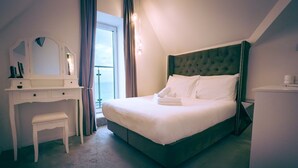 A hotel room with a bed, a desk, a chair, a mirror, and a window. - Standard Double Room (Newquay)