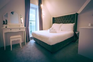 Hotellihuone, jossa on sänky, työpöytä, tuoli, peili ja ikkuna.