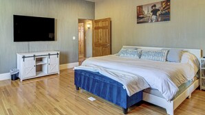 Un dormitorio con una cama, un televisor, una puerta de madera y un cuadro en la pared.