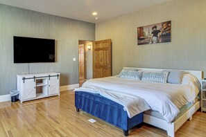 Ein Schlafzimmer mit einem Bett, einem Fernseher, einer Holztür und einem Bild an der Wand.