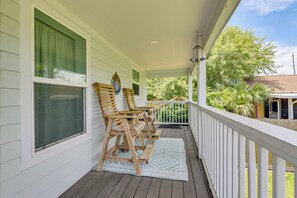 A porch with wooden chairs, a patterned rug, and a white railing. - 1 Mi to Beach & Bay! Group Getaway in Galveston (Galveston)