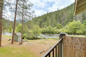 A river, a small shed, and a wooden deck with a railing.
