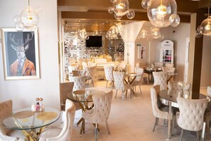 Un vestíbul d'hotel amb cadires tapissades de blanc, una taula de cafè de vidre i un quadre gran a la paret.