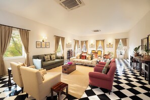 A living room with a checkered floor, a sofa, armchairs, and a coffee table. - Tree of Life Sariska Manor (Rajgarh)