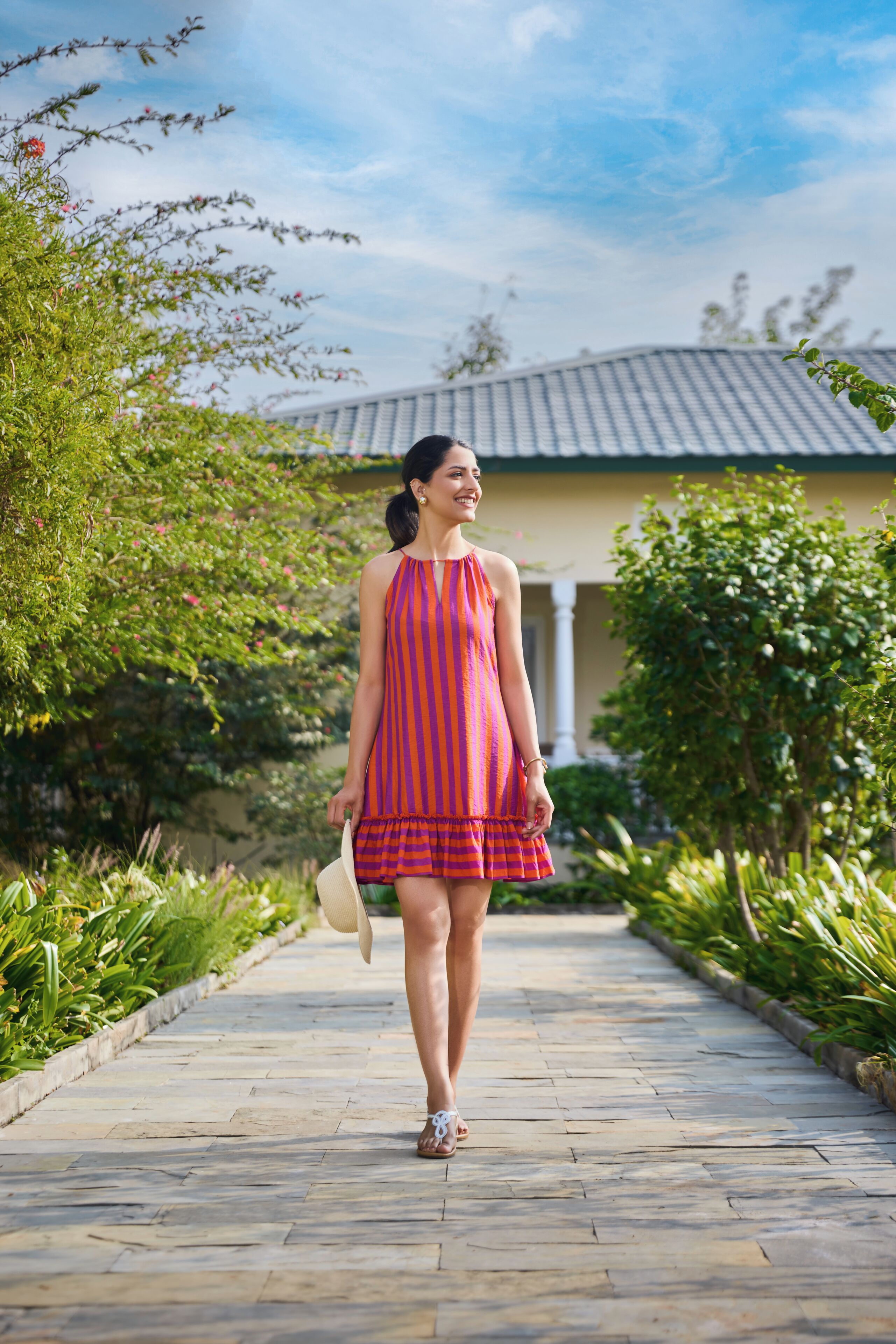 A woman walking on a paved pathway with greenery on both sides.