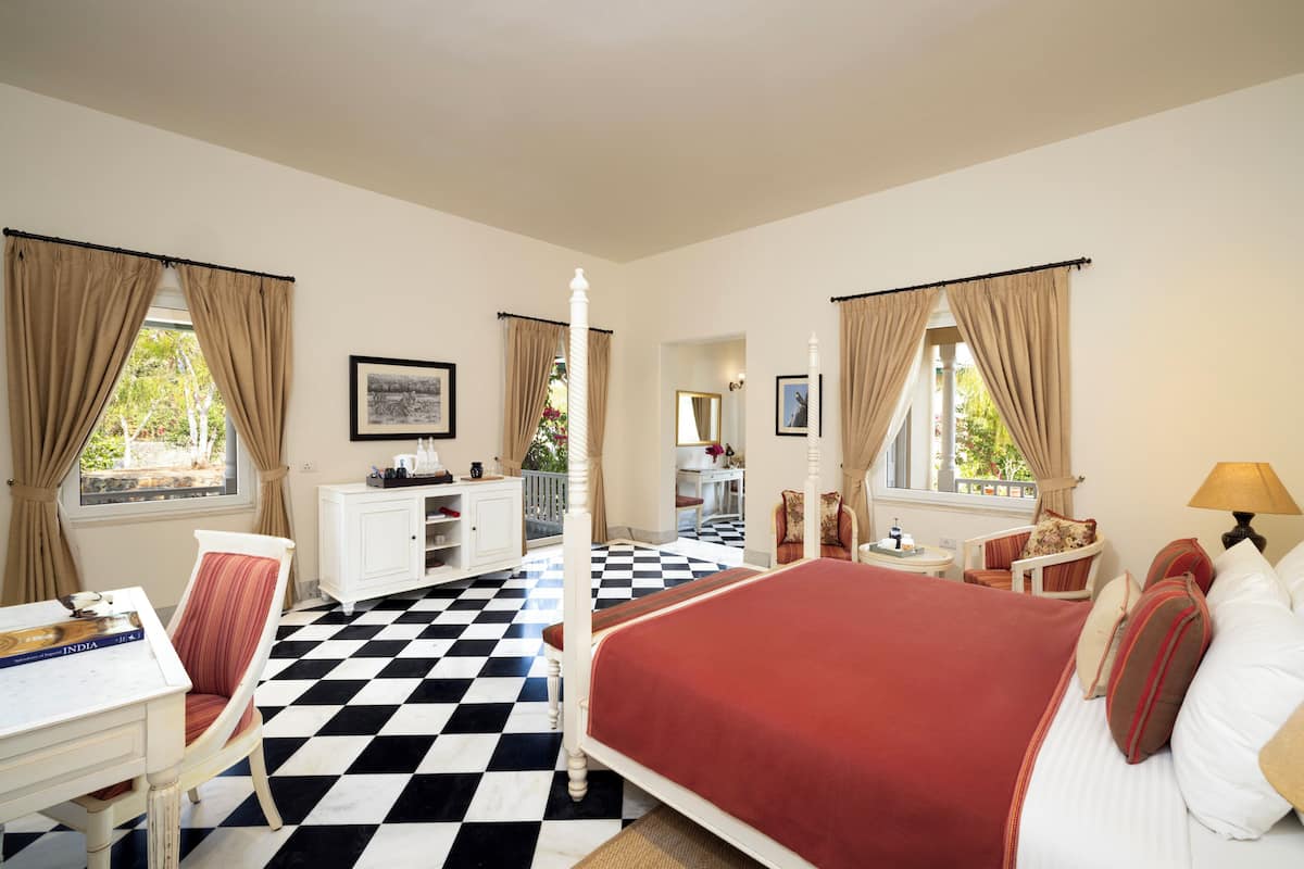 A bedroom with a checkered floor, a four-poster bed, a desk, and a chair.