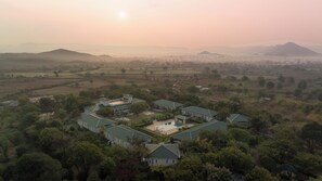 A residential area with multiple houses, a swimming pool, and a hilly landscape in the background.