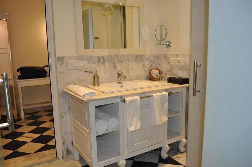 A bathroom with a white vanity, a mirror, a sink, and a towel rack.
