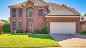 A two-story house with a garage, a front lawn, and a brick facade. - Arlington Home: Pool Oasis Near AT&T Stadium (Grand Prairie)