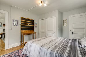 Une chambre à coucher avec un lit, une armoire en bois, une porte et un luminaire.