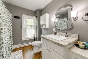 Une salle de bain équipée de toilettes, d’un lavabo, d’un miroir et d’un rideau de douche.