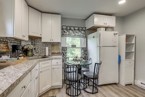 A kitchen with white cabinets, a marble countertop, a glass table, and black chairs. - 2 Mi to Beach & Boardwalk! New London Haven (New London)