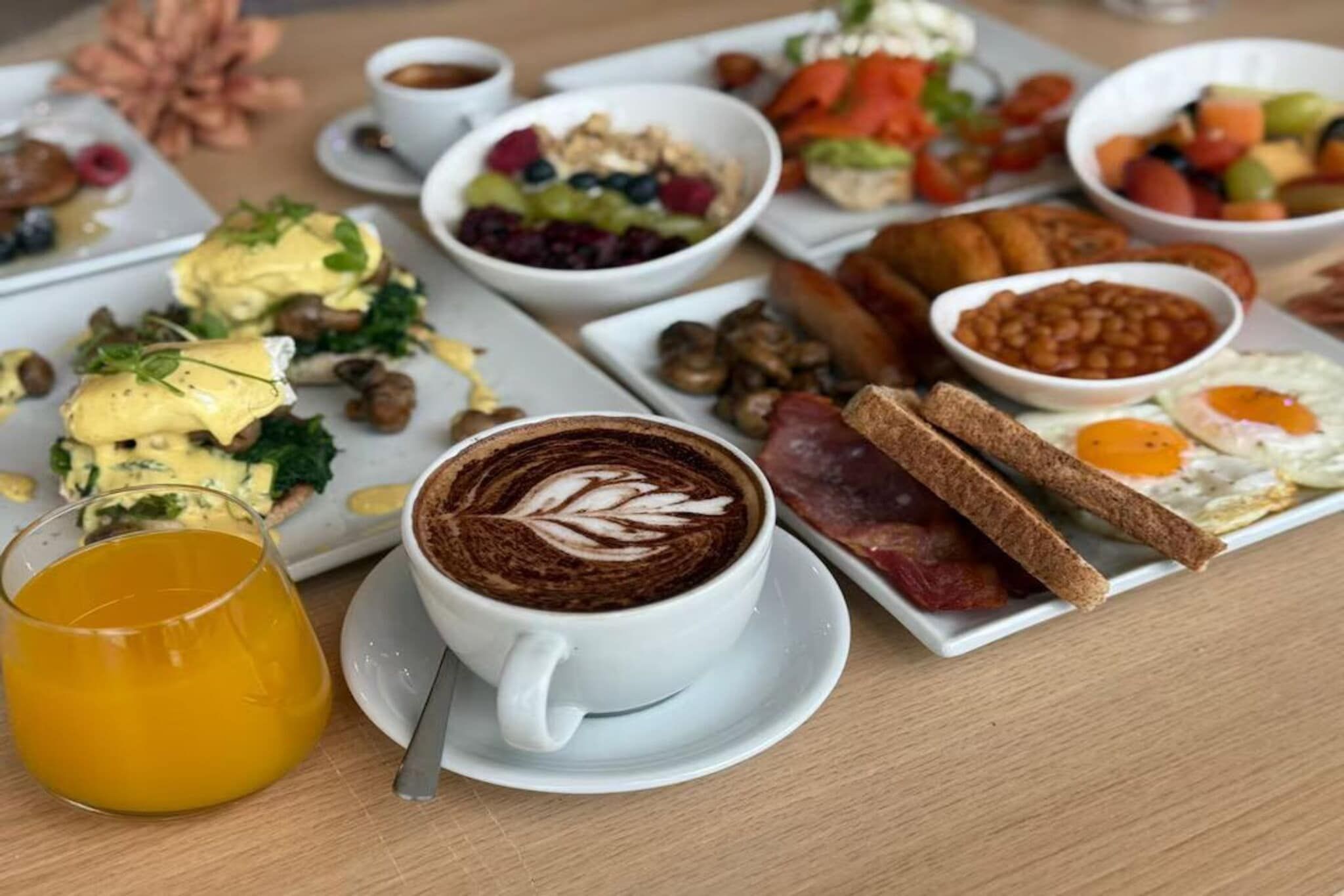 A breakfast setting with various dishes, including eggs, toast, and a cup of coffee with latte art.