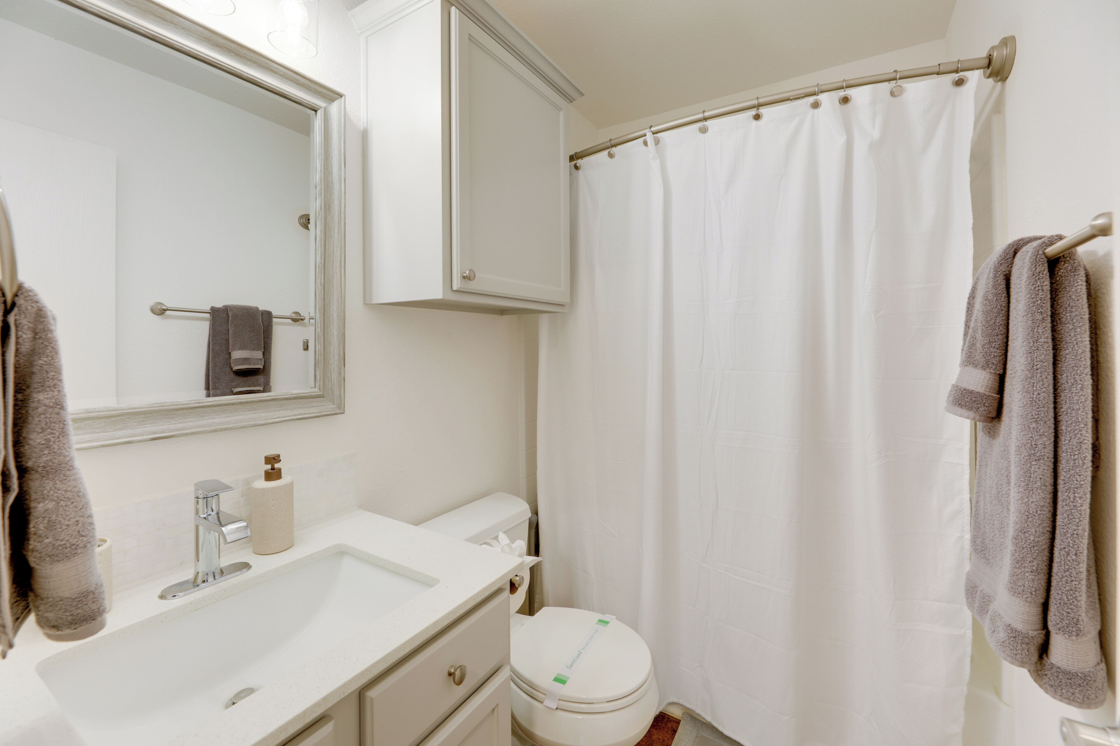 Une salle de bain avec un lavabo blanc, un miroir et des toilettes.