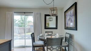 A dining area with a round table, four chairs, a chandelier, a large mirror, and a framed picture on the wall. - Private Yard & Deck! Group-Friendly Haven in Manor (Manor)