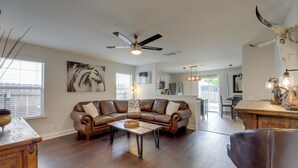 A spacious living room with a leather sectional sofa, a wooden coffee table, and a ceiling fan. - Private Yard & Deck! Group-Friendly Haven in Manor (Manor)