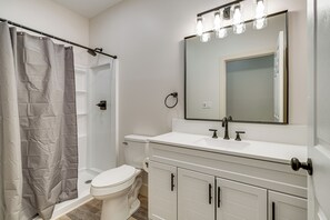 Et badeværelse med brusebad, toilet, vask og spejl.