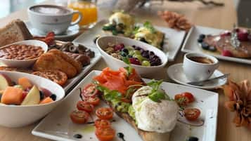 A breakfast buffet with various dishes including toast, beans, smoked salmon, and fresh fruit.