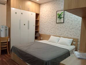 Ein Schlafzimmer mit einem Bett, einem Holzschrank und einem Schreibtisch mit Lampe.