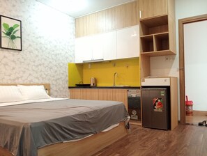 Ein gemütliches Schlafzimmer mit Bett, einer kleinen Küchenzeile und einem Kühlschrank.