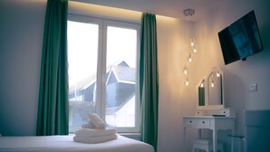 Ein Hotelzimmer mit einem Bett, einem Schreibtisch, einem Spiegel und einem an der Wand befestigten Fernseher.