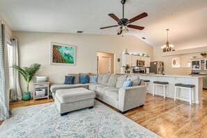 A spacious living area with a sectional sofa, a ceiling fan, and a kitchen in the background. - Pool, Hot Tub, Outdoor Kitchen Near Cocoa Beach (Rockledge)