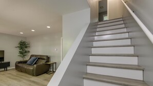 A staircase with a modern design, a leather sofa, and a small table in a living room area. - Modern Home Minutes to Mystic, Casinos and Ocean (Groton)