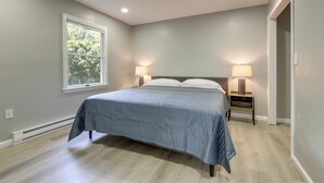 A bedroom with a bed, two bedside lamps, a window, and a door. - Modern Home, Minutes to Mystic, Casinos and Ocean (Groton)