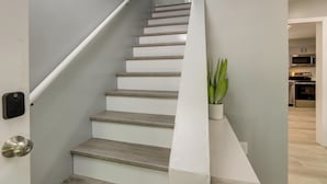 A staircase with a handrail, a potted plant, and a modern kitchen in the background. - Modern Home, Minutes to Mystic, Casinos and Ocean (Groton)