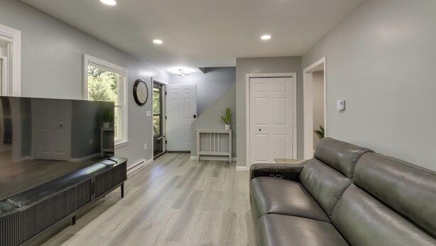 A modern living room with a leather sofa, a flat-screen TV, and a built-in entertainment unit. - Modern Home, Minutes to Mystic, Casinos and Ocean (Groton)