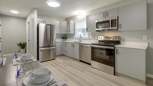A modern kitchen with stainless steel appliances, light wood flooring, and a clean, minimalist design. - Modern Home, Minutes to Mystic, Casinos and Ocean (Groton)