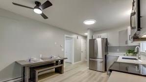 A modern kitchen with a built-in oven, a refrigerator, and a dining area with a bench. - Modern Home, Minutes to Mystic, Casinos and Ocean (Groton)