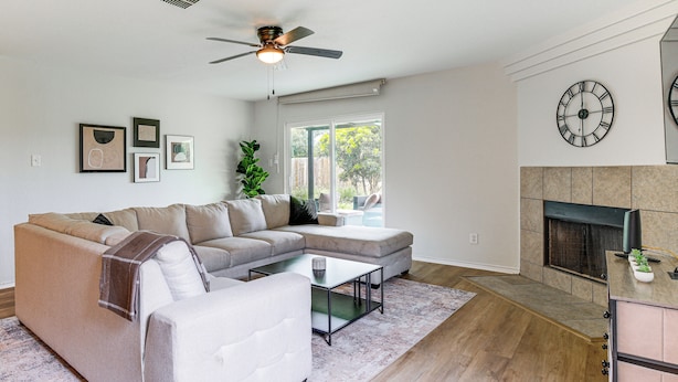 A living room with a sectional sofa, a coffee table, a fireplace, and a ceiling fan. - Pool Table & Patio! Group Hub, 4 Mi to SeaWorld (San Antonio)