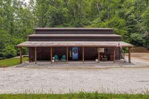 Un chalet en bois doté d’une véranda, de deux chaises, d’un banc et d’un drapeau.