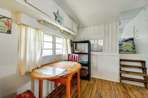 A compact kitchen with a wooden table, a chair, a black shelving unit, and a staircase. - Heated Pool, Games & Socials! Zephyrhills Home (Zephyrhills)