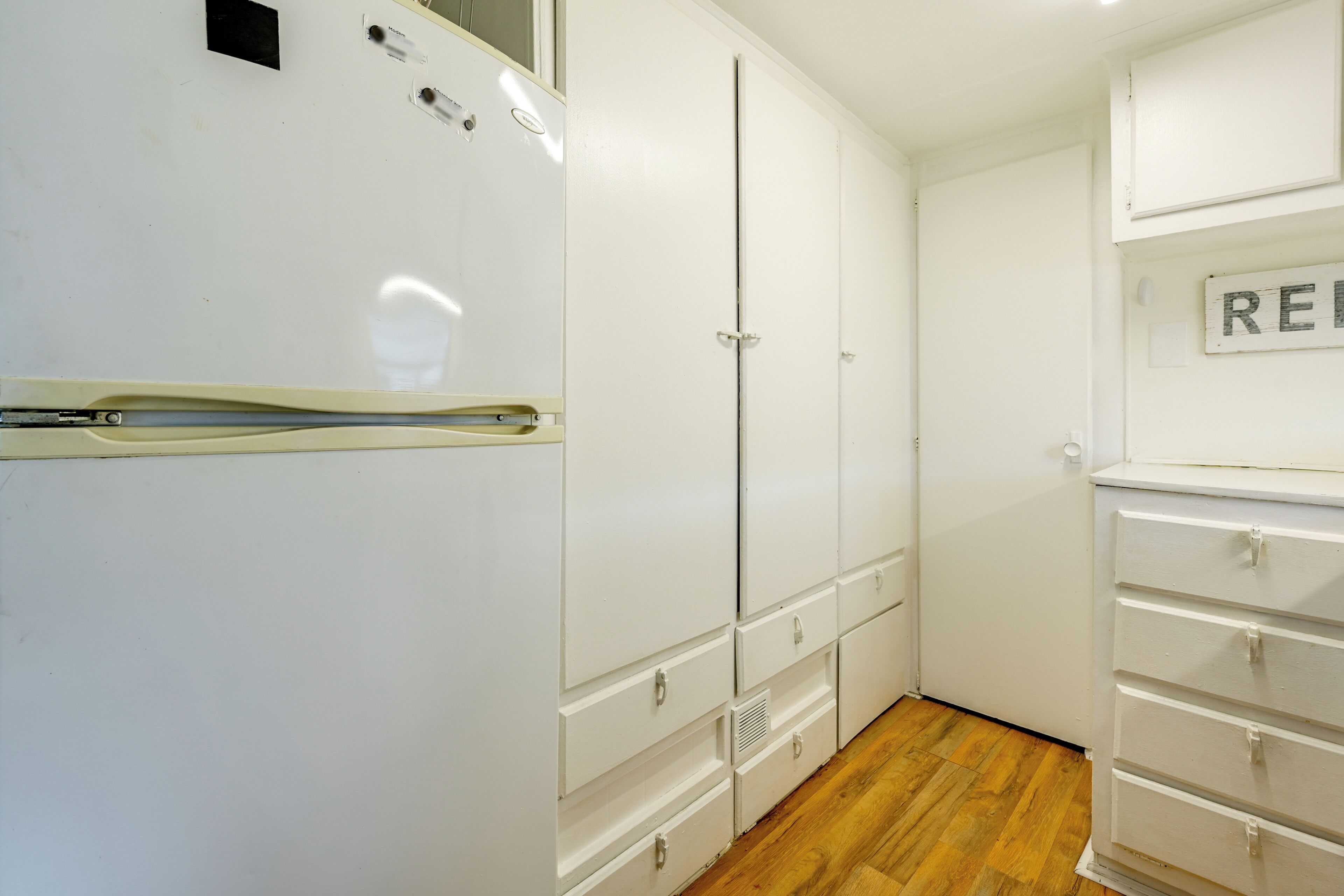 Una habitación con un armario blanco, un aparador blanco y suelo de madera.
