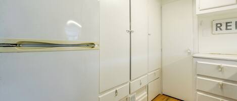 Una habitación con un armario blanco, un aparador blanco y suelo de madera.