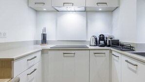 Eine moderne Küche mit weißen Schränken, einer Arbeitsplatte, einem Wasserkocher, einer Kaffeemaschine und einem Toaster.