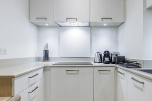 Eine moderne Küche mit weißen Schränken, einer Arbeitsplatte, einem Wasserkocher, einer Kaffeemaschine und einem Toaster.
