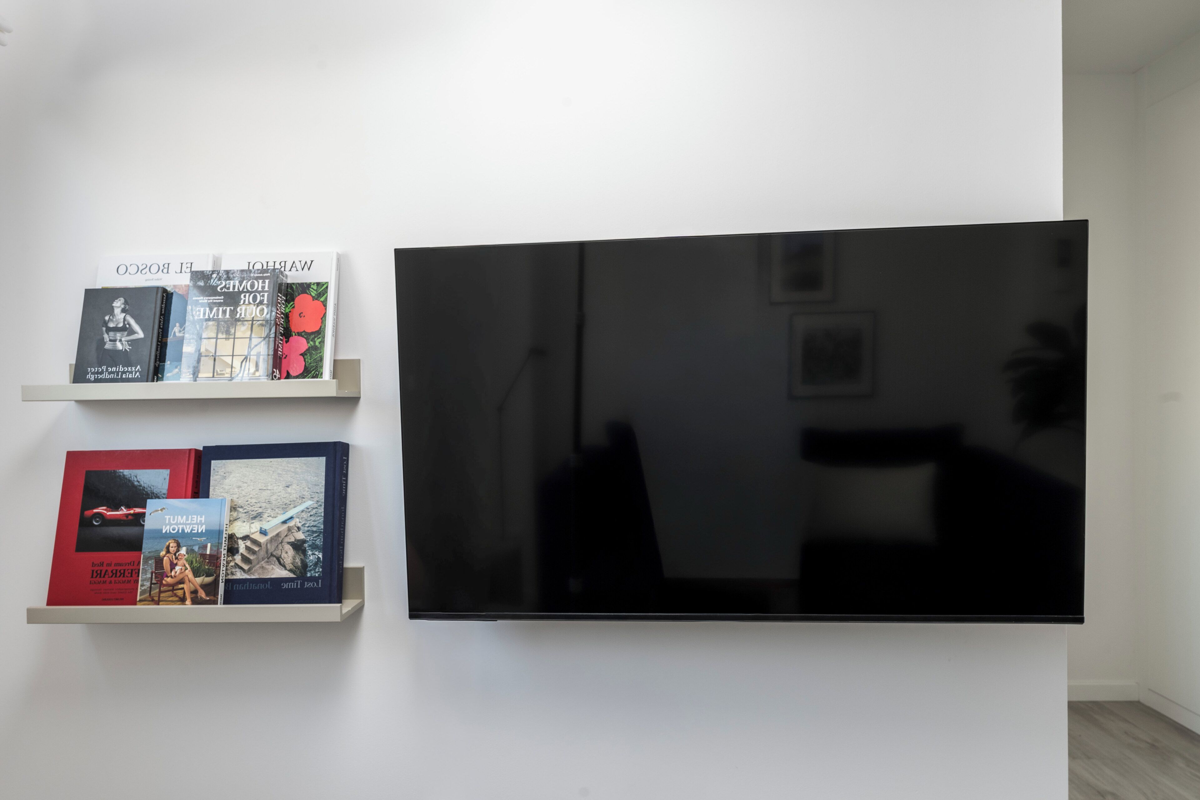 En väggmonterad TV med platt skärm, med två bokhyllor placerade under den.